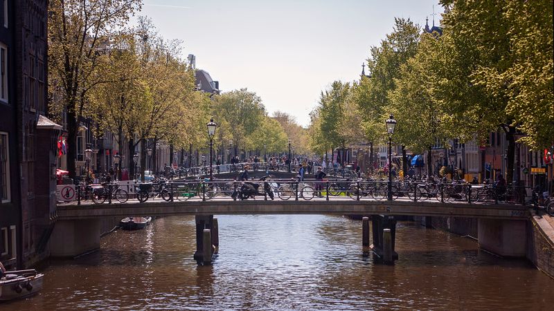Sunny canal bridge lined with parked bicycles