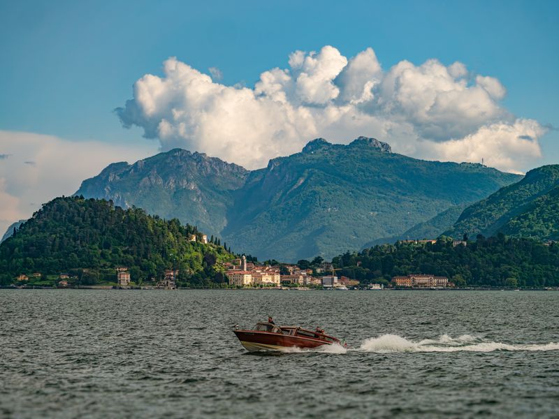 Rent a Boat for the Day: Croatia vs Riviera vs Lake Como Classic wooden boat on Lake Como, framed by the mountains