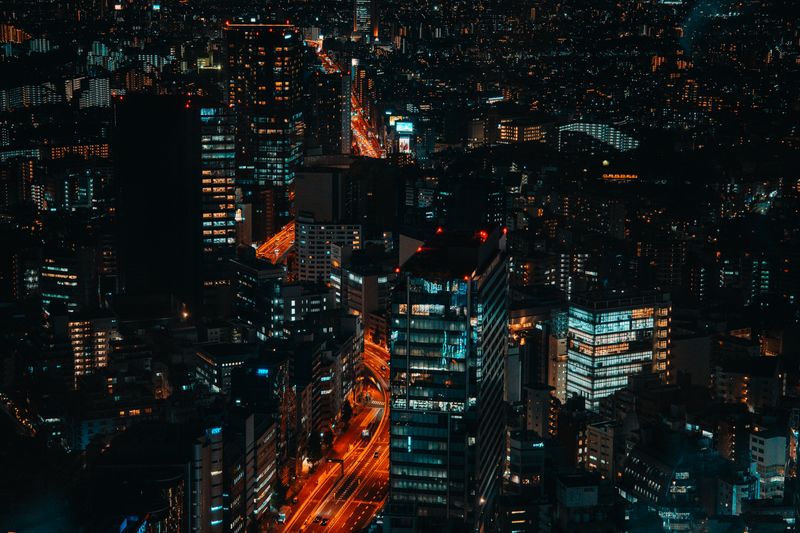 Aerial night view of illuminated expressway cutting through skyscrapers