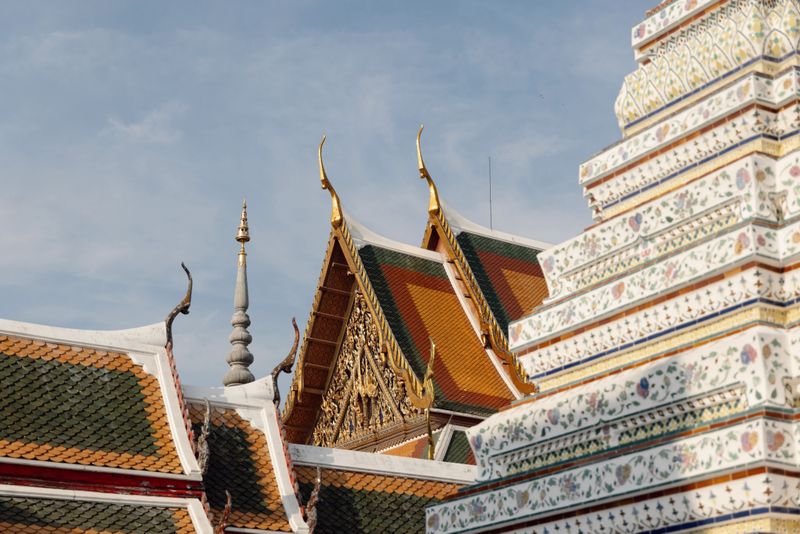 Layered temple roofs and decorated stupa against clear sky