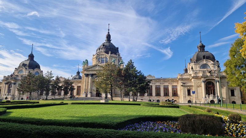 Szechenyi bath facade with manicured lawn and flowers