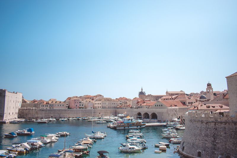 Old Town harbor with boats and city walls under blue sky