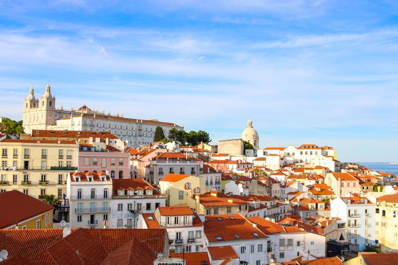 Alfama rooftops with cathedral towers and dome against river backdrop