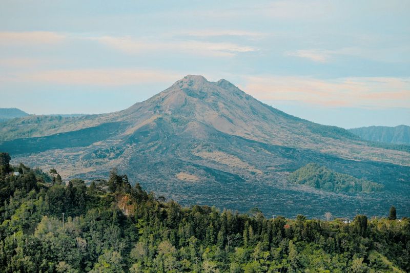 Mount Batur's peak rising above forested foothills at dusk