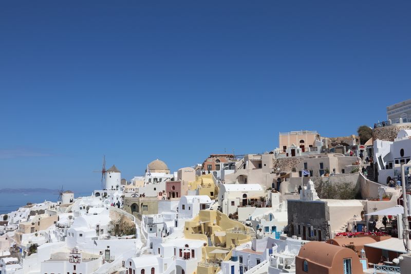 Wide village view with whitewashed houses and windmill under blue sky
