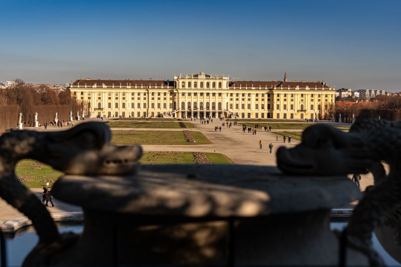 Palace framed by blurred stone dragon fountain statues at sunset