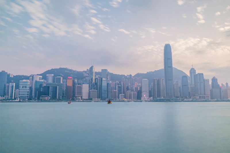 Pale skyline reflected across calm Victoria Harbour at dusk