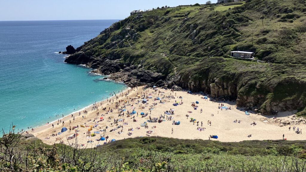 Turquoise water and sandy beach at Porthcurno, Cornwall, seen from the coast path